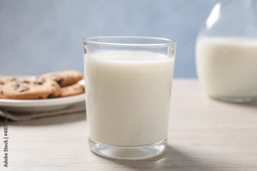 Glass of fresh milk near cookies on white table Glass of fresh milk near cookies on white table