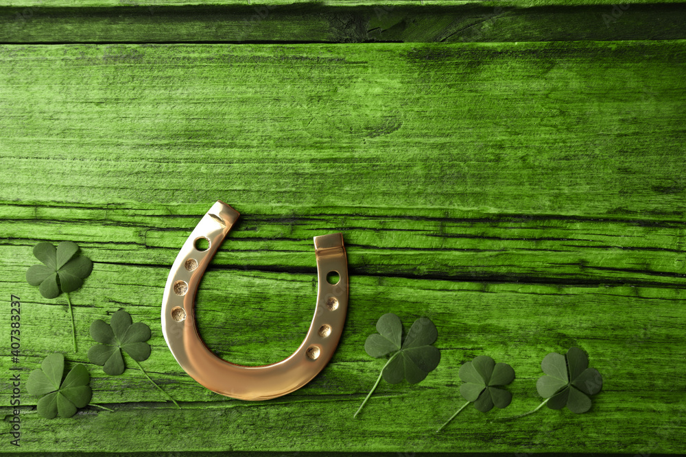 Clover leaves and horseshoe on green wooden table, flat lay with space for text. St. Patrick's Day celebration