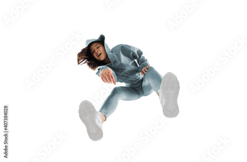 Pointing. Young stylish woman in modern street style outfit isolated on white background, shot from the bottom. Caucasian fashionable model in shoes and overalls, musician, rapper performing.