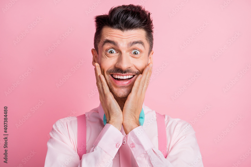 Photo portrait of excited man touching face cheeks with two hands isolated on pastel pink colored background Photo portrait of excited man touching face cheeks with two hands isolated on pastel pink colored background