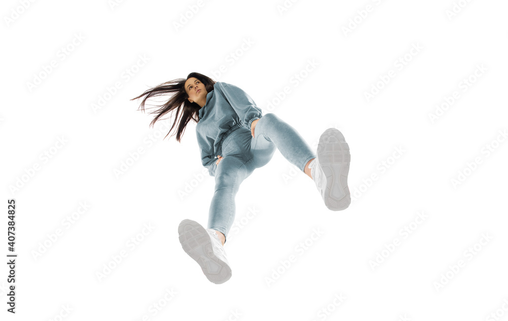 Looking on. Young stylish woman in modern street style outfit isolated on white background, shot from the bottom. Caucasian fashionable model in shoes and overalls, musician, rapper performing. Looking on. Young stylish woman in modern street style outfit isolated on white background, shot from the bottom. Caucasian fashionable model in shoes and overalls, musician, rapper performing.