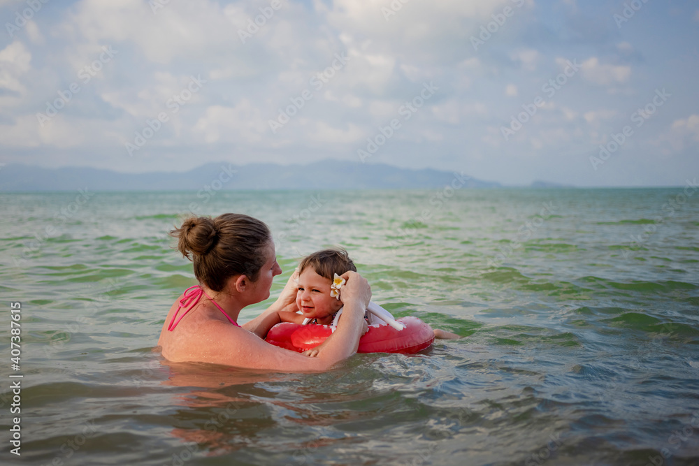 Cheerful girl swimming with her mom at sea.
