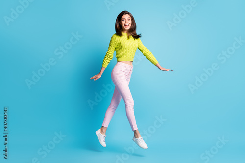 Fototapeta Naklejka Na Ścianę i Meble -  Full length photo portrait of excited girl walking jumping up isolated on pastel blue colored background