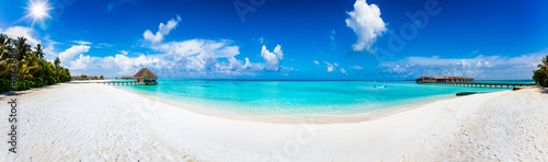 Fototapeta Naklejka Na Ścianę i Meble -  Wide panoramic view of a tropical beach with turquoise sea, Palm trees and water lodges over the ocean in the Maldives islands
