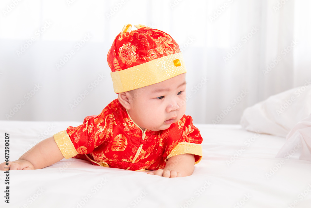 Adorable Asian boy in red Chinese Costume clothes lie on the stomach try crawling on white bed, cute innocent infant baby start crying feel uncomforted difficult to move forward and need mother help Adorable Asian boy in red Chinese Costume clothes lie on the stomach try crawling on white bed, cute innocent infant baby start crying feel uncomforted difficult to move forward and need mother help