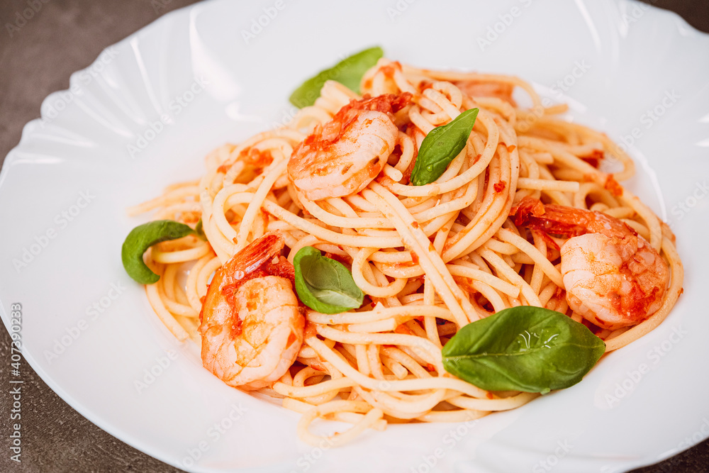 Spaghetti with tomato sauce, basil and shrimps. Italian cuisine. Fresh healthy light main course, serving on a plate