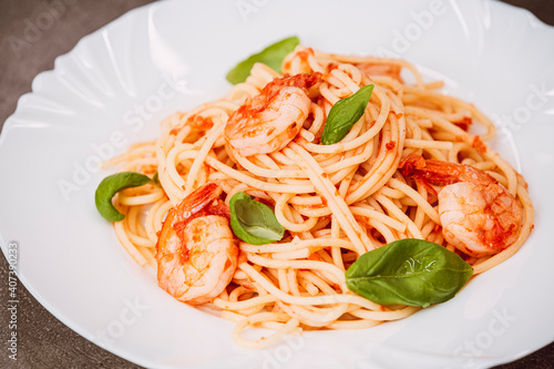 Spaghetti with tomato sauce, basil and shrimps. Italian cuisine. Fresh healthy light main course, serving on a plate