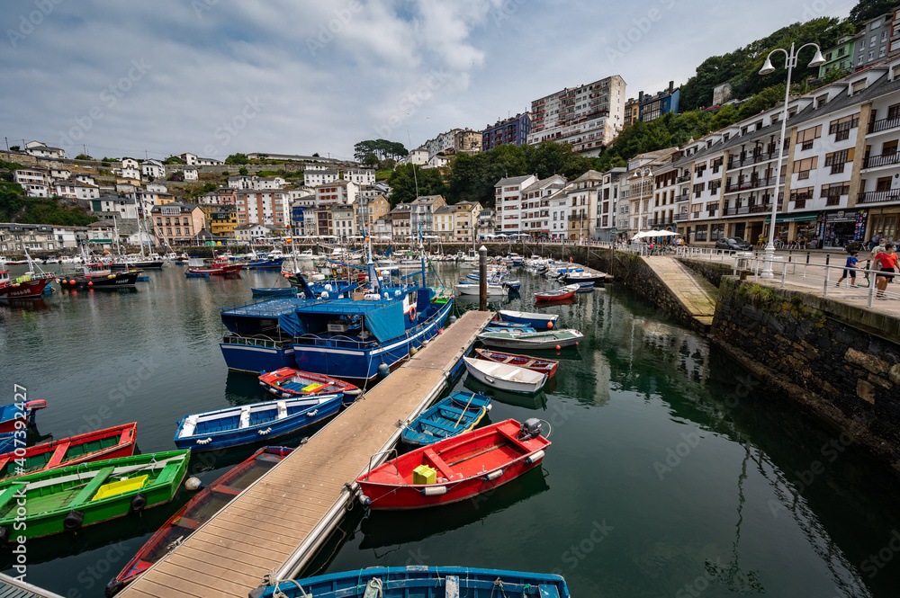 Fototapeta premium The Austurian port village of Luarca showing boats in harbor and tourists on promenade