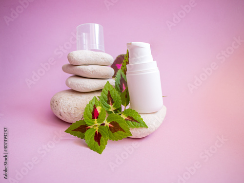 white plastic jar with  dispenser and  gentle caring organic hand and body cream, on smooth textured rounded stones on  pink background.