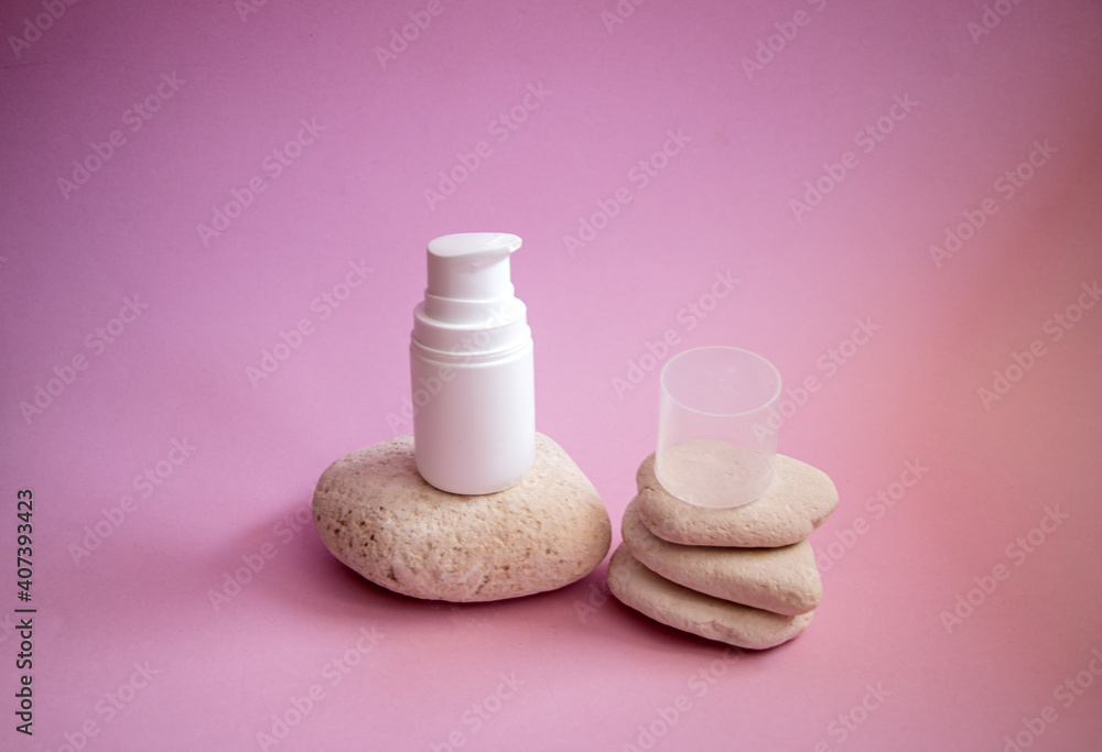 white plastic jar with  dispenser and  gentle caring organic hand and body cream, on smooth textured rounded stones on  pink background.