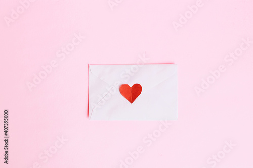 Top view of mini red heart shape on envelope with pink background