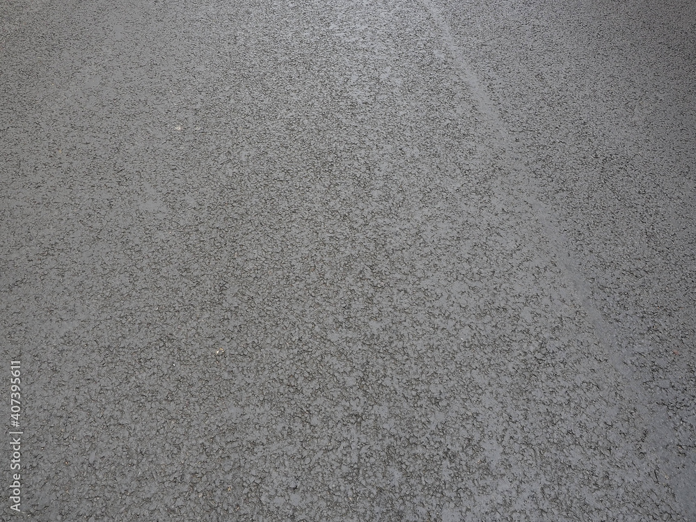 A fragment of a road with a dark gray freshly paved asphalt. Full screen photo. A fragment of a road with a dark gray freshly paved asphalt. Full screen photo.