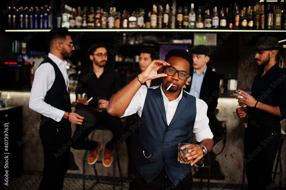 Stylish african american man against group of handsome retro well-dressed guys gangsters spend time at club, drinking on bar counter. Multiethnic male bachelor mafia party in restaurant. Stylish african american man against group of handsome retro well-dressed guys gangsters spend time at club, drinking on bar counter. Multiethnic male bachelor mafia party in restaurant.