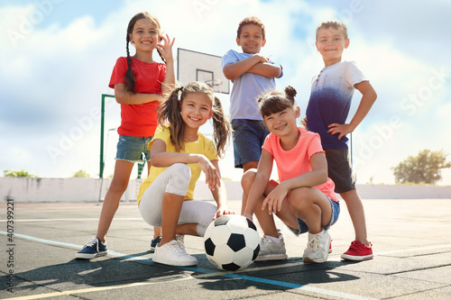 Fototapeta Naklejka Na Ścianę i Meble -  Cute children with soccer ball at sports court on sunny day. Summer camp
