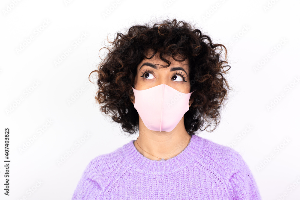 young beautiful caucasian woman wearing medical mask standing against white wall looking aside into empty space thoughtful young beautiful caucasian woman wearing medical mask standing against white wall looking aside into empty space thoughtful