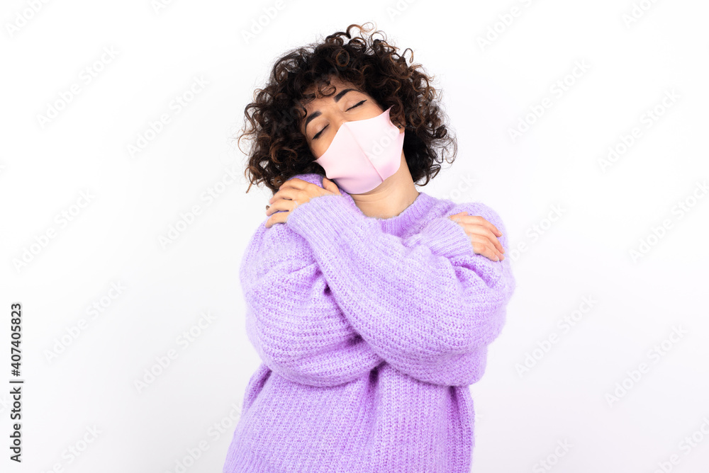 young beautiful caucasian woman wearing medical mask standing against white wall Hugging oneself happy and positive, smiling confident. Self love and self care young beautiful caucasian woman wearing medical mask standing against white wall Hugging oneself happy and positive, smiling confident. Self love and self care