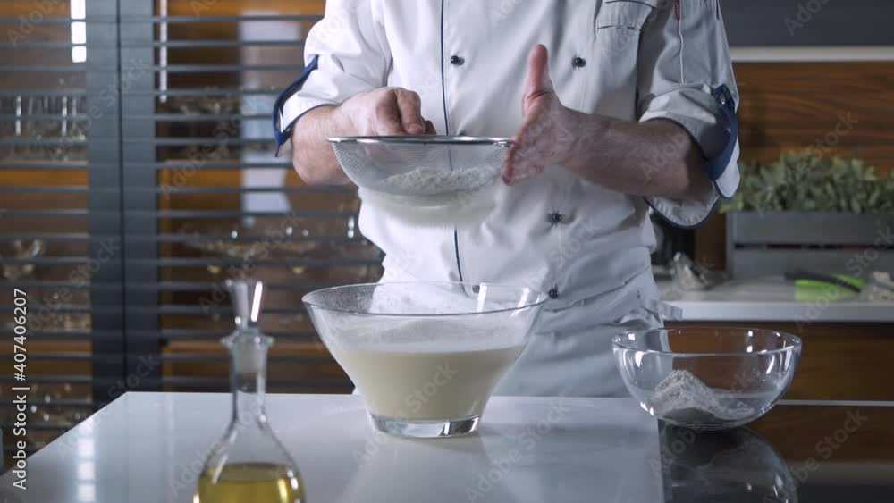 Professional Chef sifting Flour for a Baking in a Restaurant Kitchen. Baker in the Uniform Making Dough for Pizza, Pasta or Pie. Cooking a Recipe. Delicious healthy Food. Slow motion Close up Professional Chef sifting Flour for a Baking in a Restaurant Kitchen. Baker in the Uniform Making Dough for Pizza, Pasta or Pie. Cooking a Recipe. Delicious healthy Food. Slow motion Close up
