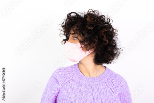 Close up side profile photo young beautiful caucasian woman wearing medical mask standing against white wall not smiling attentive listen concentrated