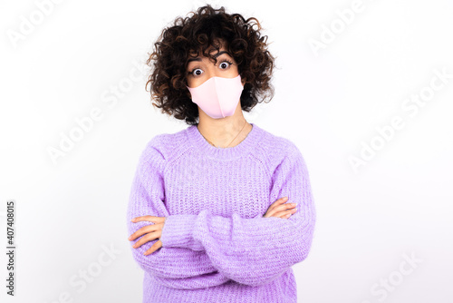 Shocked embarrassed young beautiful caucasian woman wearing medical mask standing against white wall keeps mouth widely opened. Hears unbelievable novelty stares in stupor © Roquillo