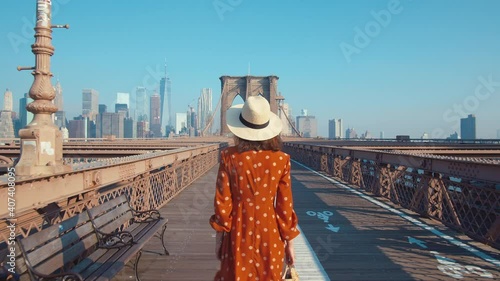 Attractive girl walking across the Brooklyn Bridge in summer