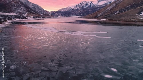 Flying over and looking down at ice layer on lake during sunset viewing the texture and patterns reflecting the colors from the sky. photo