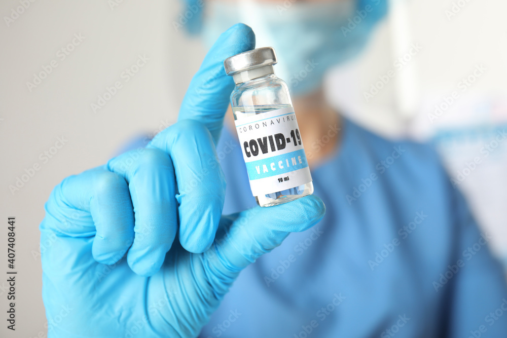 Doctor holding vial with vaccine against Covid-19 indoors, closeup