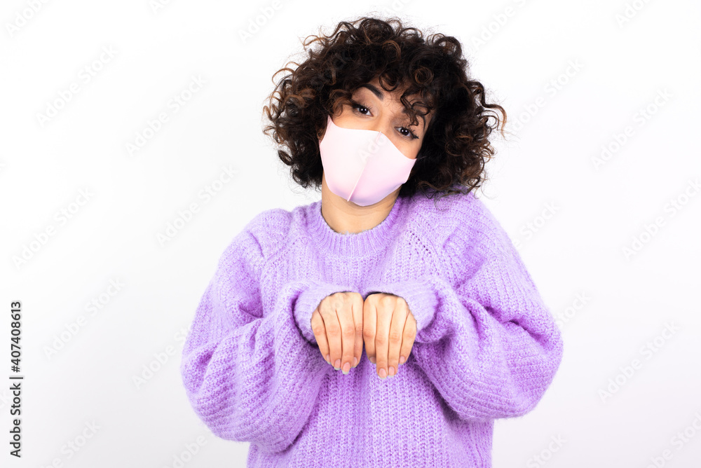young beautiful caucasian woman wearing medical mask standing against white wall makes bunny paws and looks with innocent expression plays with her little kid young beautiful caucasian woman wearing medical mask standing against white wall makes bunny paws and looks with innocent expression plays with her little kid