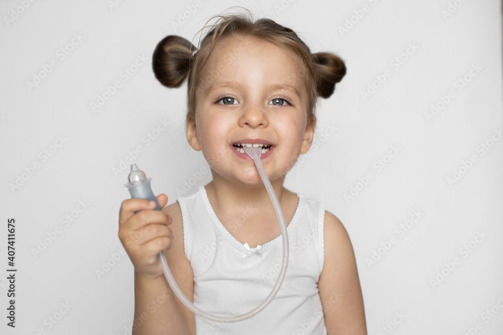 Happy child promoting device for vacuum suction of nasal snot and mucus. Cute blond little girl with two ponytails, posing to camera with smile, holding in hands nasal cleaner aspirator Happy child promoting device for vacuum suction of nasal snot and mucus. Cute blond little girl with two ponytails, posing to camera with smile, holding in hands nasal cleaner aspirator