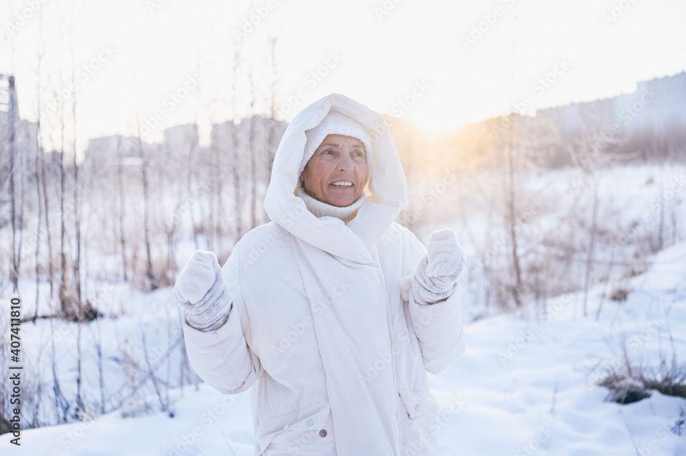 Happy elderly senior mature woman in white warm outwear playing with snow in sunny winter outdoors. Retired healthy people holiday vacation winter activities, active lifestyle concept. Happy elderly senior mature woman in white warm outwear playing with snow in sunny winter outdoors. Retired healthy people holiday vacation winter activities, active lifestyle concept.