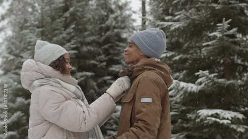 Wallpaper Mural Medium shot of young mixed-race woman and her boyfriend standing together in winter forest. Woman fixing clothes on her boyfriend Torontodigital.ca