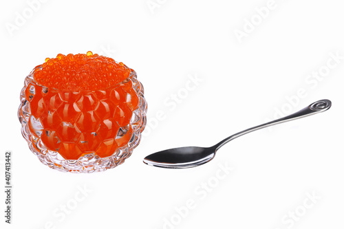 red caviar in a glass caviar bowl with a spoon lying next to it on a white isolated background