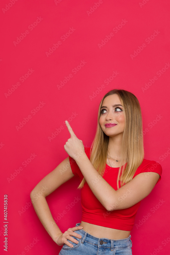 Smiling Young Woman In Red Top Is Pointing Up And Watching Smiling Young Woman In Red Top Is Pointing Up And Watching