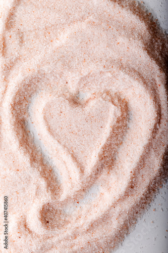 Pink Himalayan salt powder with a heart-shaped mark on it. Food background.