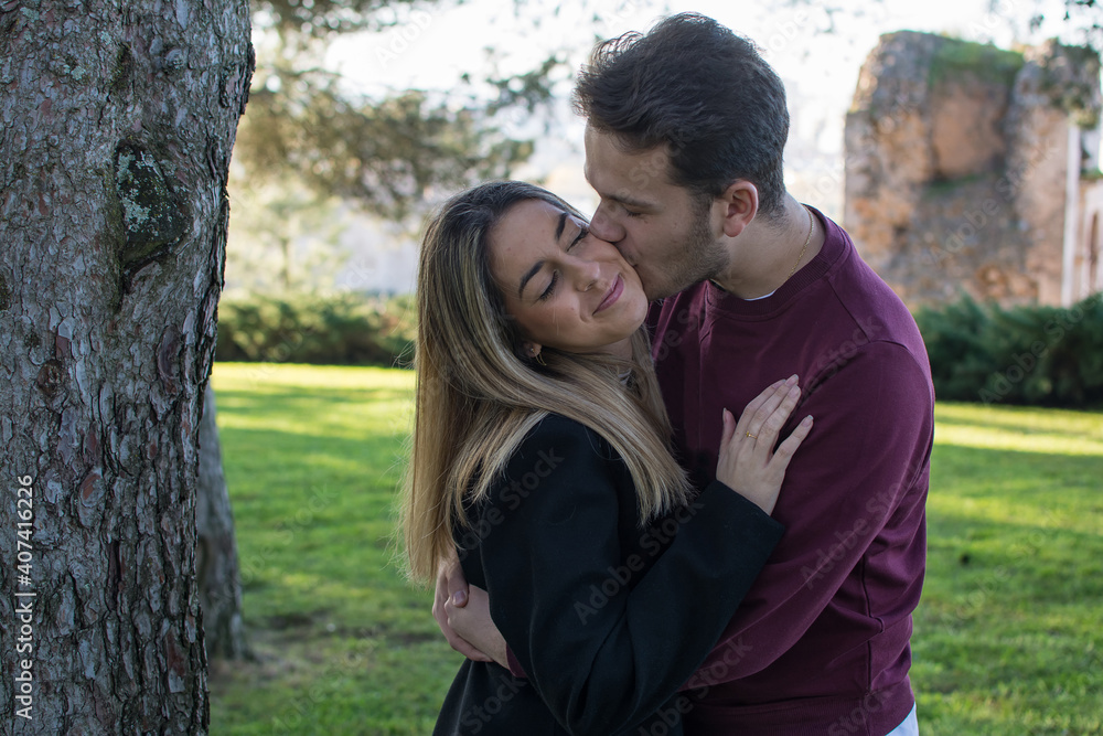 Lovers Kissing Outdoors In The Park. Happy Lovers By A Park. In Love Lovers Kissing Outdoors In The Park. Happy Lovers By A Park. In Love