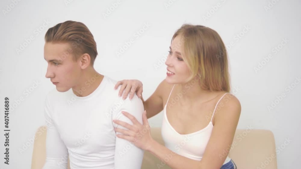 Young man sits sad with his back to his girlfriend. Young man sits sad with his back to his girlfriend.