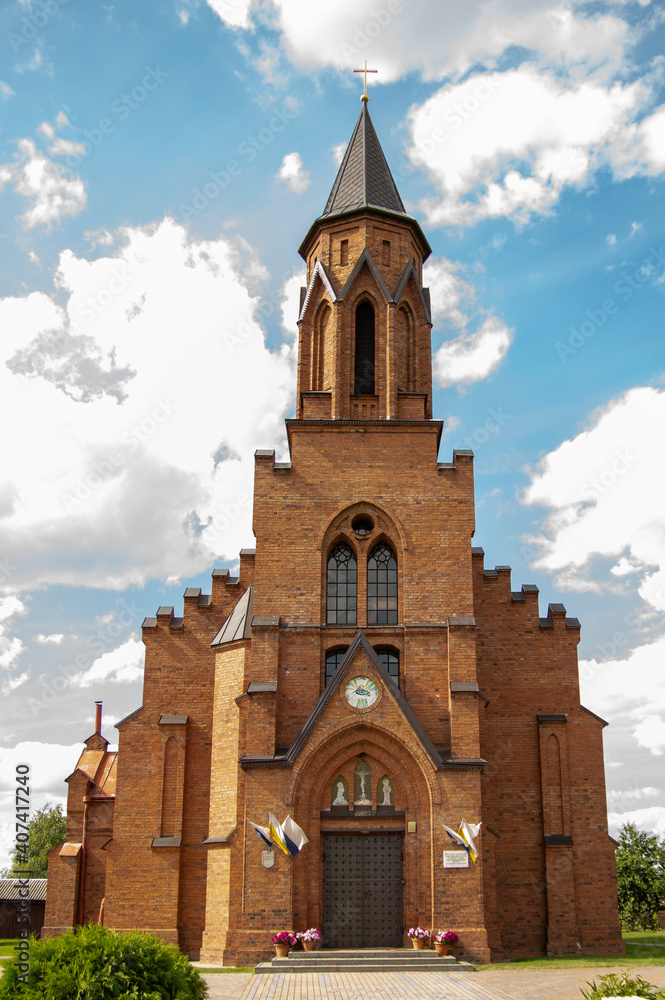 Photo of a red brick Catholic church against a bright blue sky