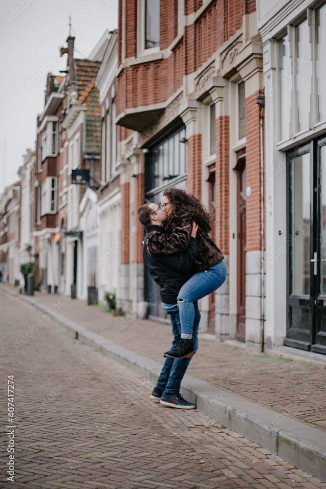 Two people in love walking around the old town in The Netherlands, hugging each other and kissing. A young woman and a man, a couple.