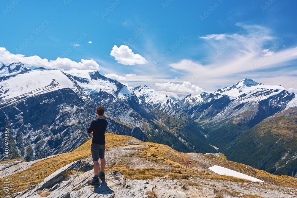 Young man standing on a cliff looking over the valley in New Zealand