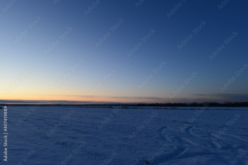 Winter dusky blue sky in a rural area over snowy fields