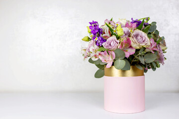 Beautiful bouquet of flowers in pink round box on a white table. Gift for holiday, birthday, Wedding, Mother's Day, Valentine's day, Women's Day. Floral arrangement in a hat box.