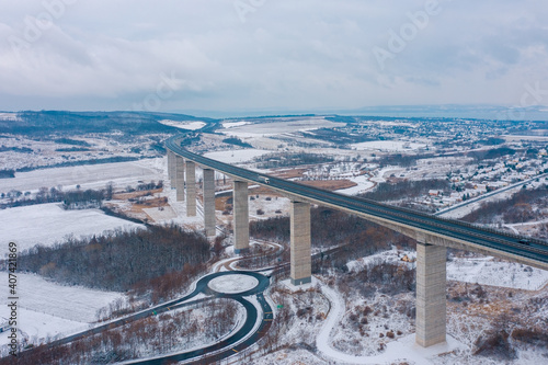 Kőröshegy, Hungary - Amazing aerial view of the famous Viaduct of Koroshegy with lake Balaton at the background. Snowy winter landscape. Hungarian name is Kőröshegyi Völgyhíd. photo