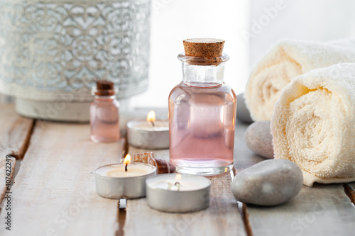 Natural organic spa products on wooden background. Essential rose oil, towel, stones. Atmosphere of relax, detention, zen. Aromatherapy. Body care, healthy lifestyle. Close up. Copy space for text.