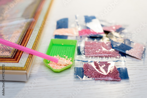 home hobby to draw a picture of rhinestones, multicolored diamond mosaic. the process of gluing a pencil of rhinestones on the canvas of the picture