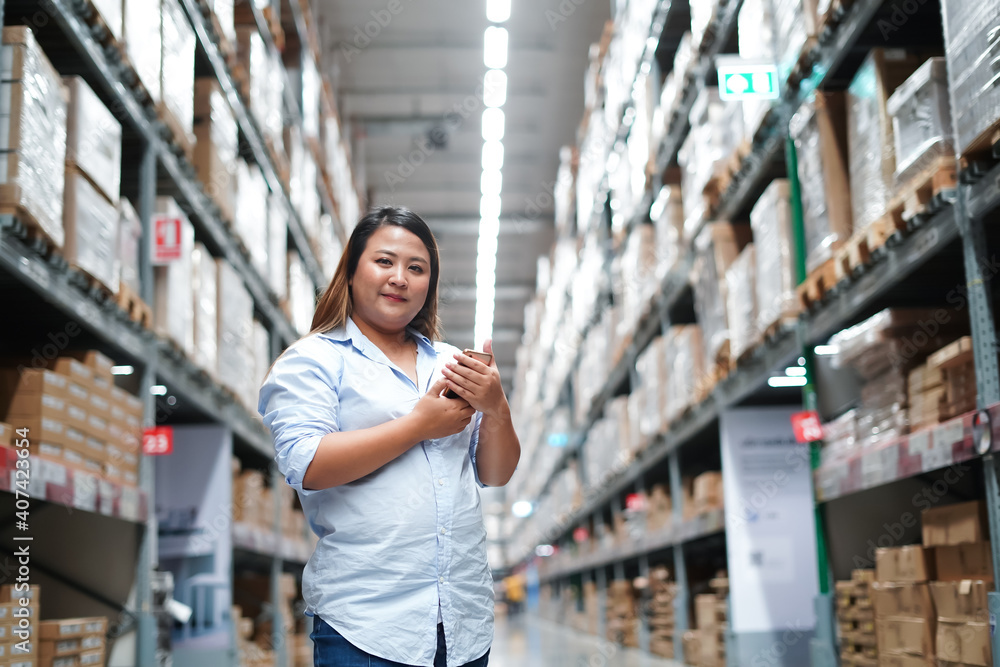 Plus size female worker inspecting box of products while working in large warehouse