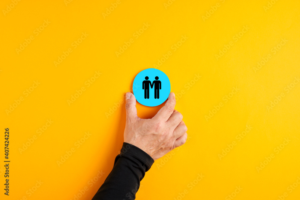 Male hand placing a blue badge with a gay couple holding hand in hand Male hand placing a blue badge with a gay couple holding hand in hand