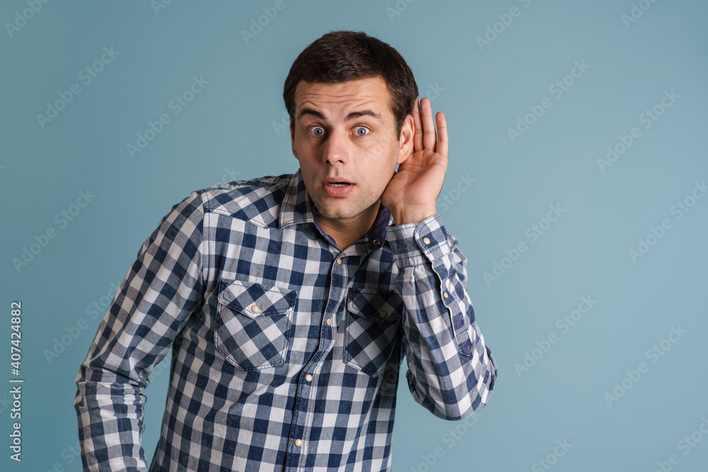 Shocked young brunette guy looking aside and overhearing Shocked young brunette guy looking aside and overhearing