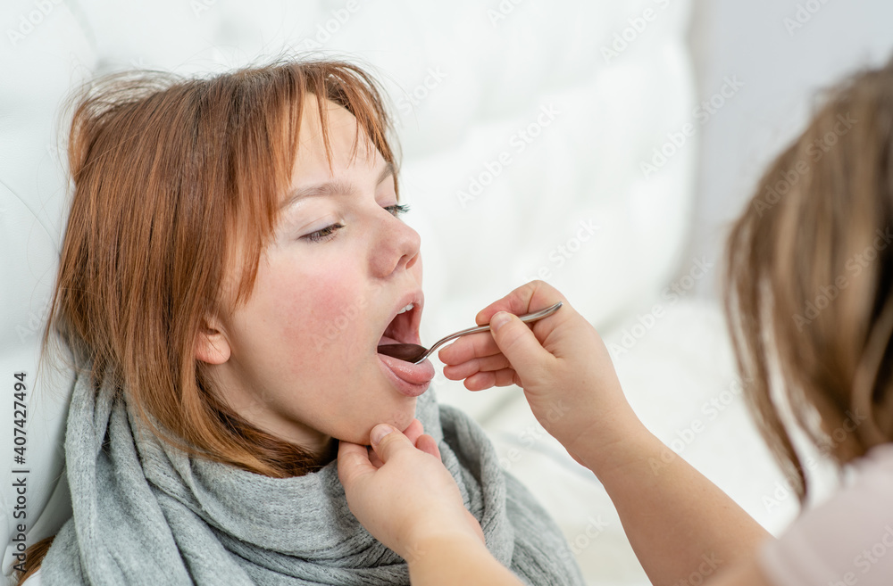 Mother examining throat of a teen sick girl at home Mother examining throat of a teen sick girl at home
