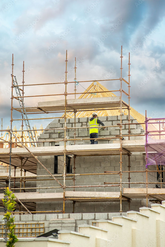 Bricklayer on a scaffolding brick a wall of concrete blocks Bricklayer on a scaffolding brick a wall of concrete blocks