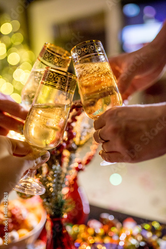 champagne glasses in the hands of friends on the background of a Christmas tree and New Year decor