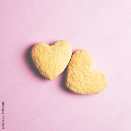 Two cookies in shape of a heart next to each other on a pink background. Pastel colors. The concept of Valentine's Day. Place for text.
